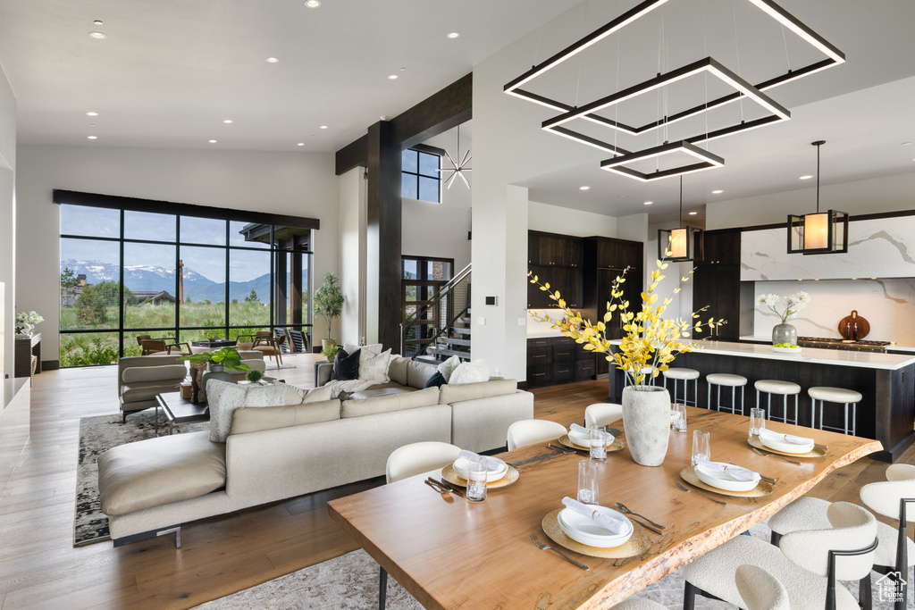 Dining area with wood finished floors, stairway, recessed lighting, a mountain view, and a towering ceiling