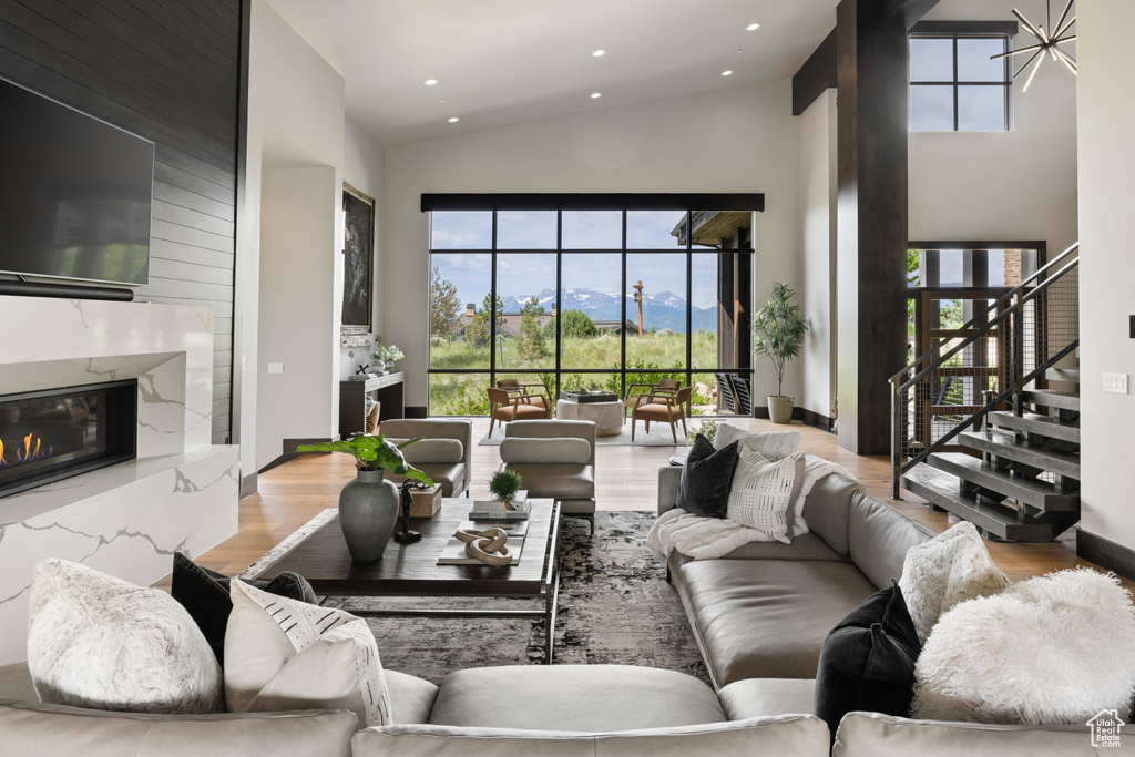 Living area featuring high vaulted ceiling, stairs, a fireplace, wood finished floors, and recessed lighting