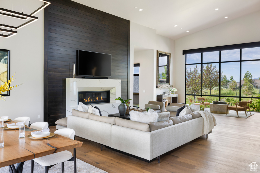 Living area with a towering ceiling, wood finished floors, recessed lighting, a fireplace, and a chandelier