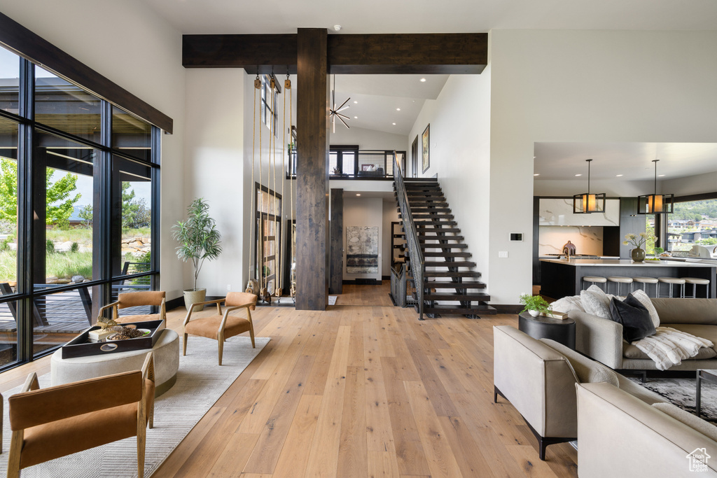 Living room featuring high vaulted ceiling, stairs, light wood-type flooring, beam ceiling, and recessed lighting