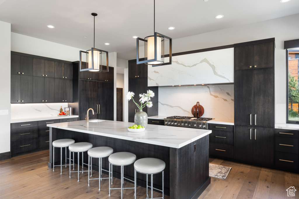 Kitchen with a breakfast bar area, backsplash, hardwood / wood-style flooring, modern cabinets, and recessed lighting