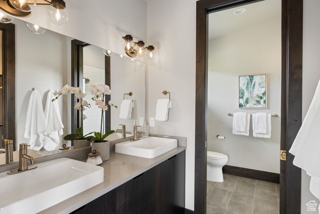 Full bath with double vanity, toilet, baseboards, and a chandelier