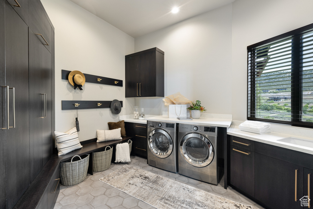 Laundry room with cabinet space, washer and clothes dryer, and light tile patterned flooring