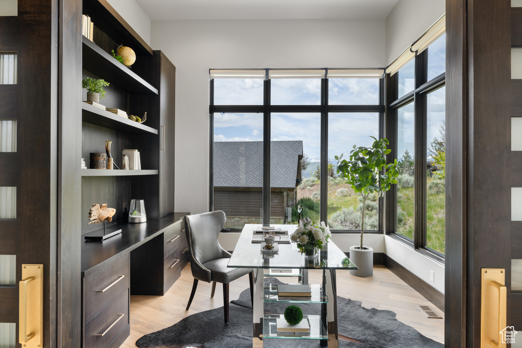 Office with light wood-style flooring and built in study area