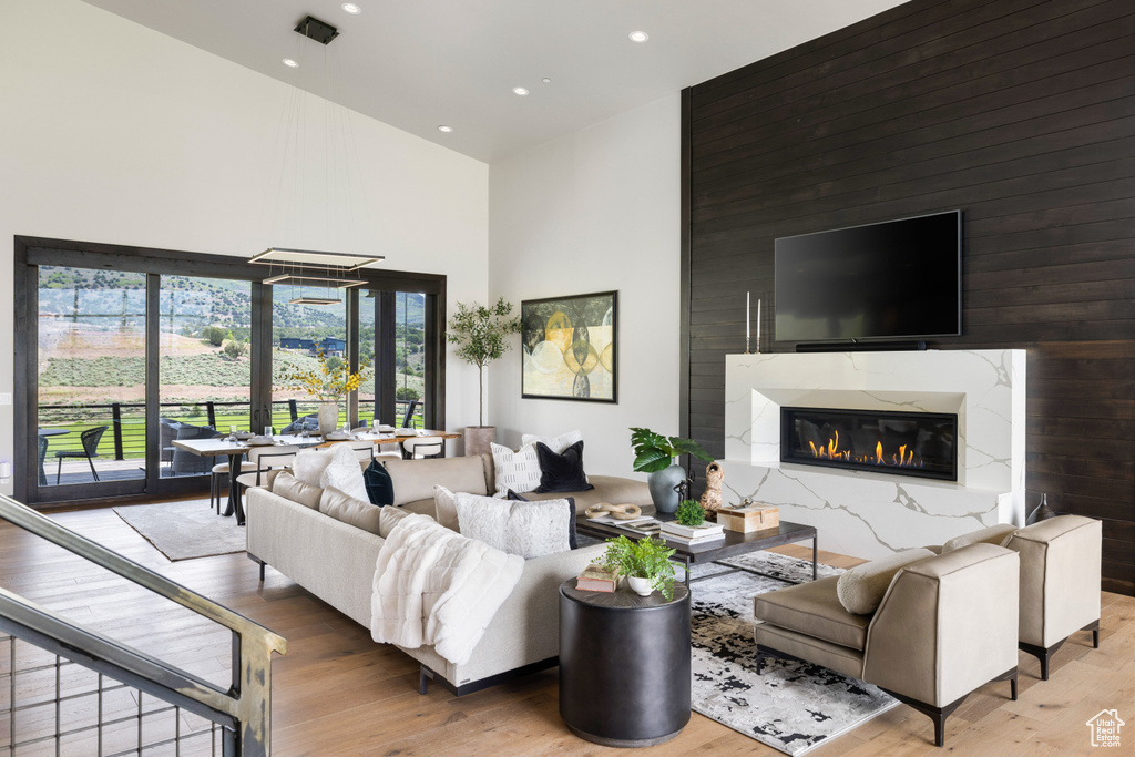 Living room with a high ceiling, wood finished floors, recessed lighting, and a premium fireplace
