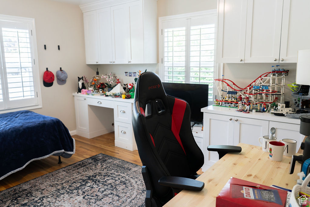 Bedroom featuring light wood-style floors, a desk, and multiple windows