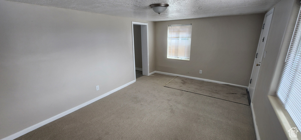 Unfurnished bedroom featuring a textured ceiling, light carpet, baseboards, and a closet