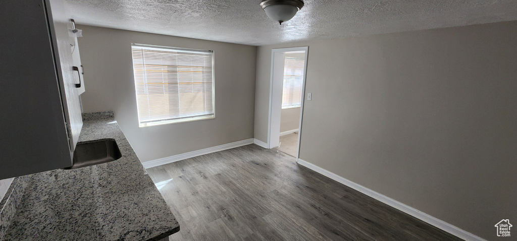 Unfurnished dining area featuring a textured ceiling, wood finished floors, and baseboards