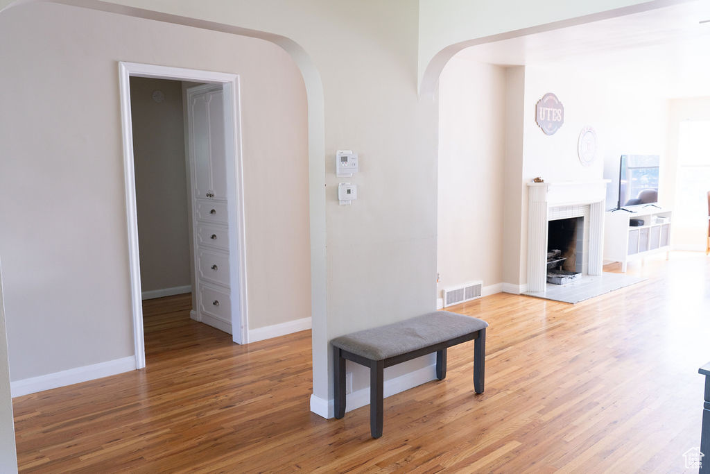 Hall with light wood-style floors, arched walkways, and baseboards