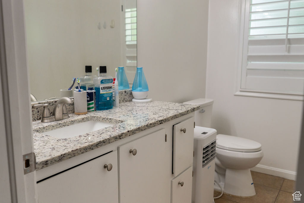 Half bathroom with vanity, toilet, plenty of natural light, and tile patterned flooring
