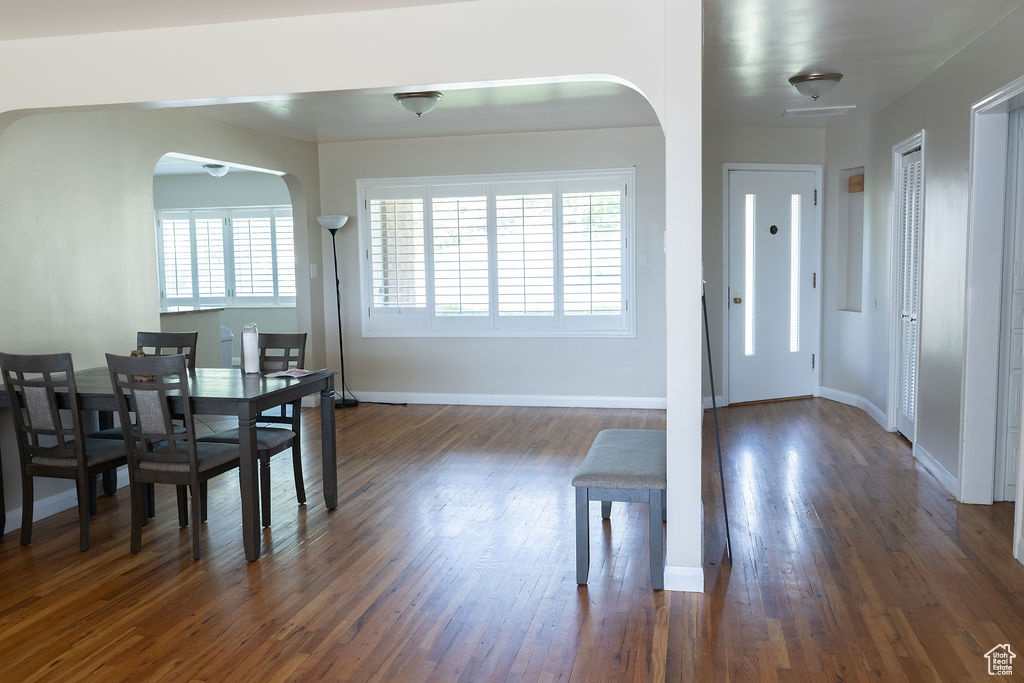 Dining area with plenty of natural light, dark wood-type flooring, arched walkways, and baseboards