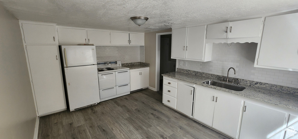 Kitchen with white appliances, a sink, dark wood-style flooring, tasteful backsplash, and white cabinets