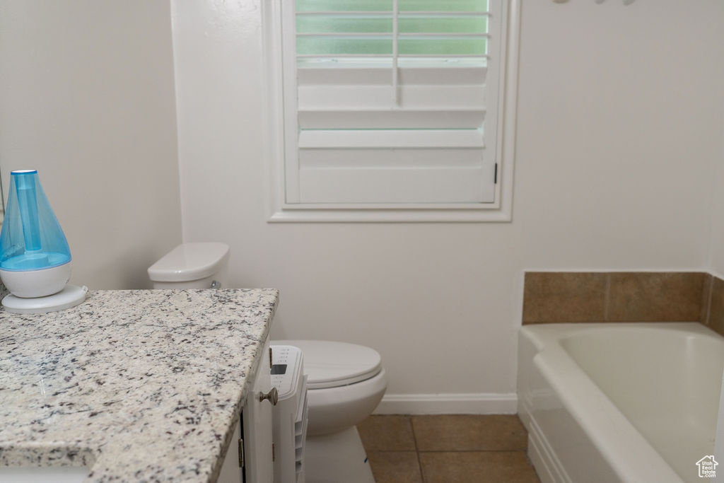 Bathroom with a garden tub, tile patterned floors, vanity, toilet, and baseboards