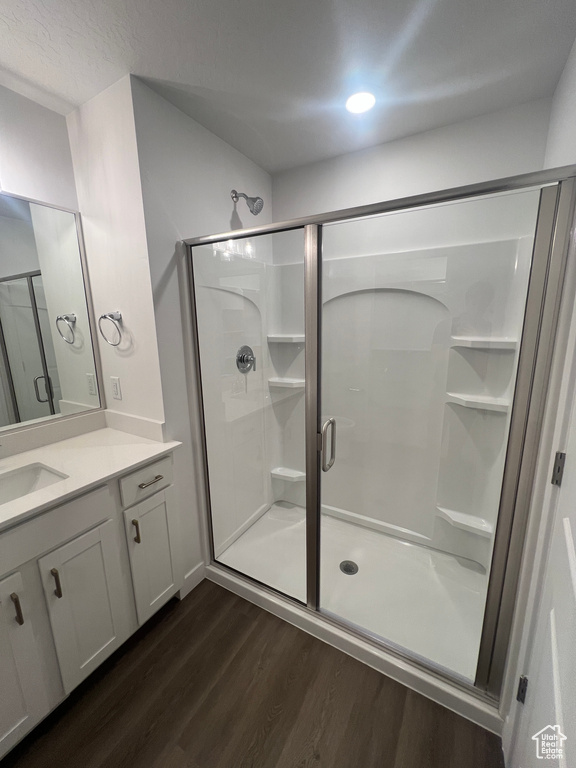 Full bath featuring wood finished floors, vanity, and a stall shower