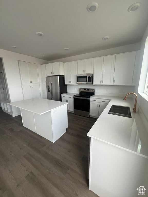 Kitchen featuring stainless steel appliances, a sink, dark wood-style flooring, white cabinets, and light countertops