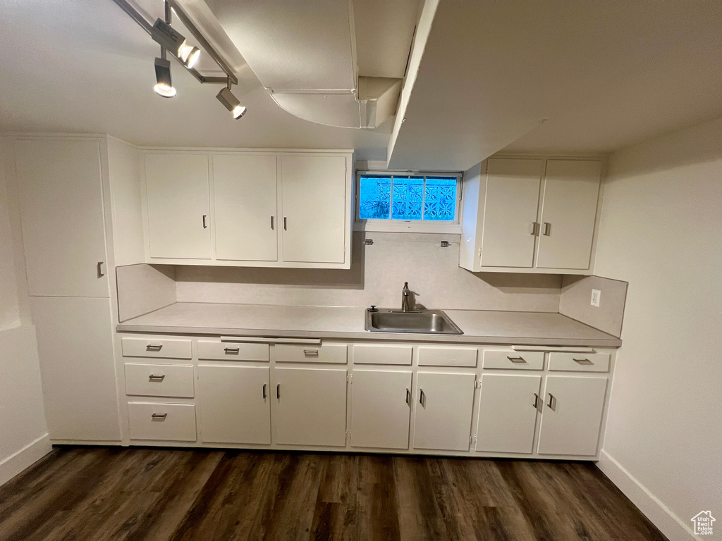 Kitchen featuring a sink, light countertops, baseboards, and white cabinets