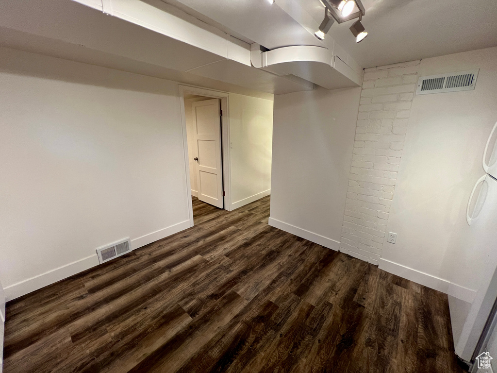 Finished below grade area featuring dark wood-type flooring and baseboards