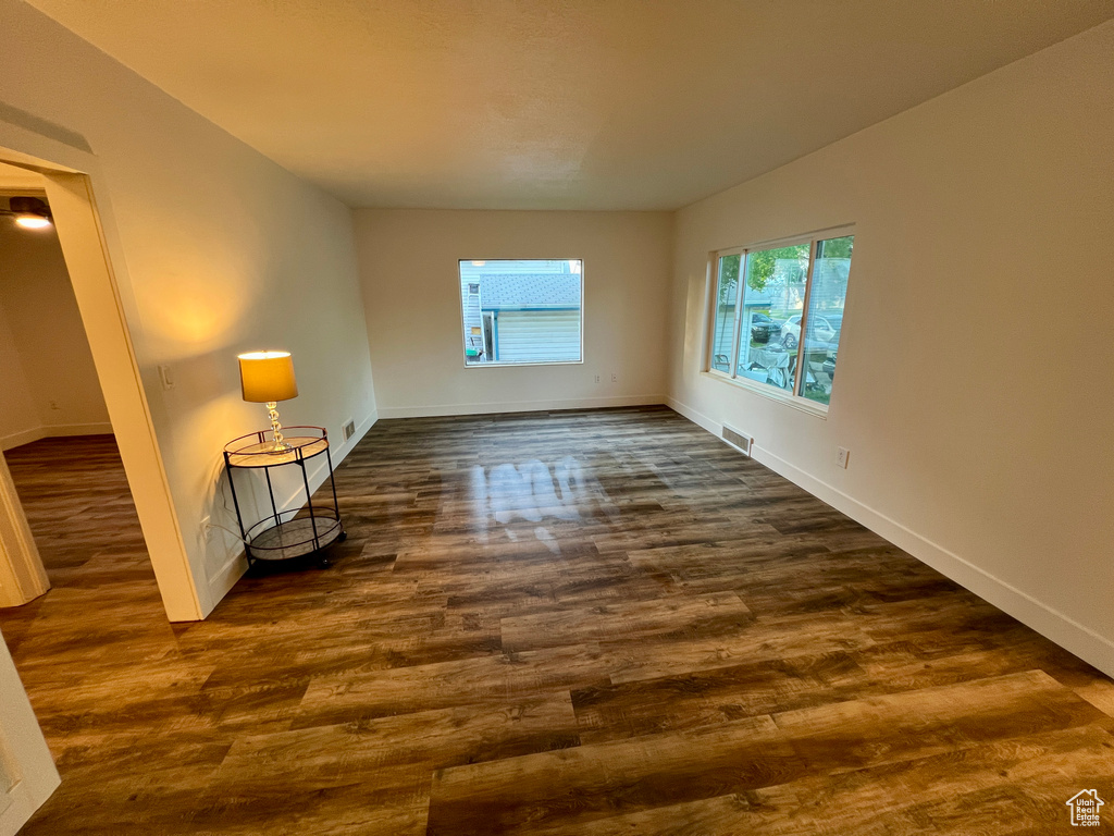 Empty room featuring dark wood-style flooring and baseboards