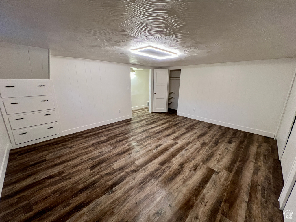 Finished below grade area featuring dark wood-style flooring, baseboards, and a textured ceiling