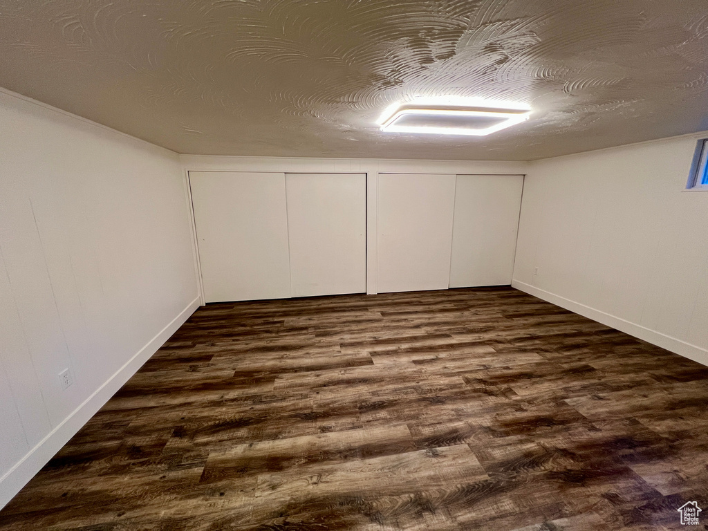 Below grade area with dark wood-style flooring and baseboards