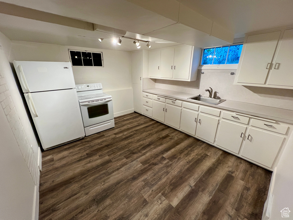 Kitchen with white appliances, a sink, light countertops, dark wood-type flooring, and white cabinetry