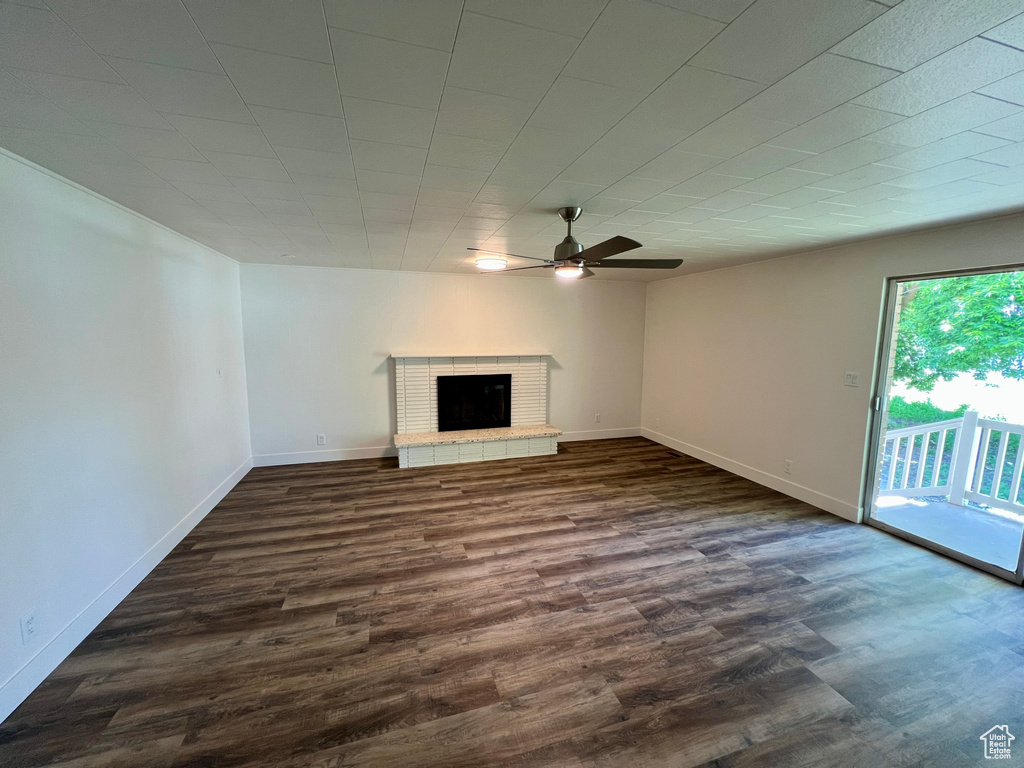 Unfurnished living room with ceiling fan, dark wood-style flooring, a fireplace, and baseboards