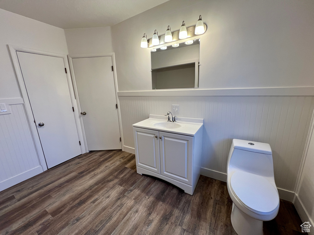 Bathroom with wainscoting, vanity, wood finished floors, and toilet