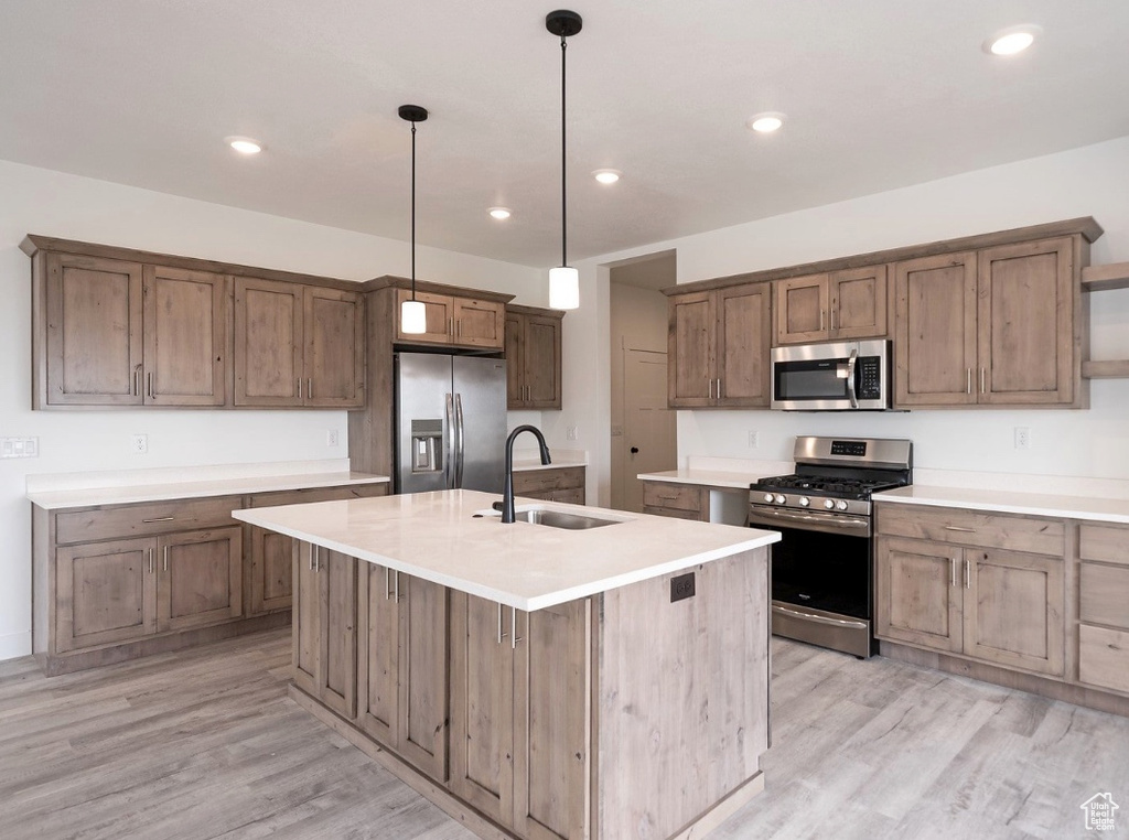 Kitchen featuring appliances with stainless steel finishes, a sink, light wood-type flooring, hanging light fixtures, and recessed lighting