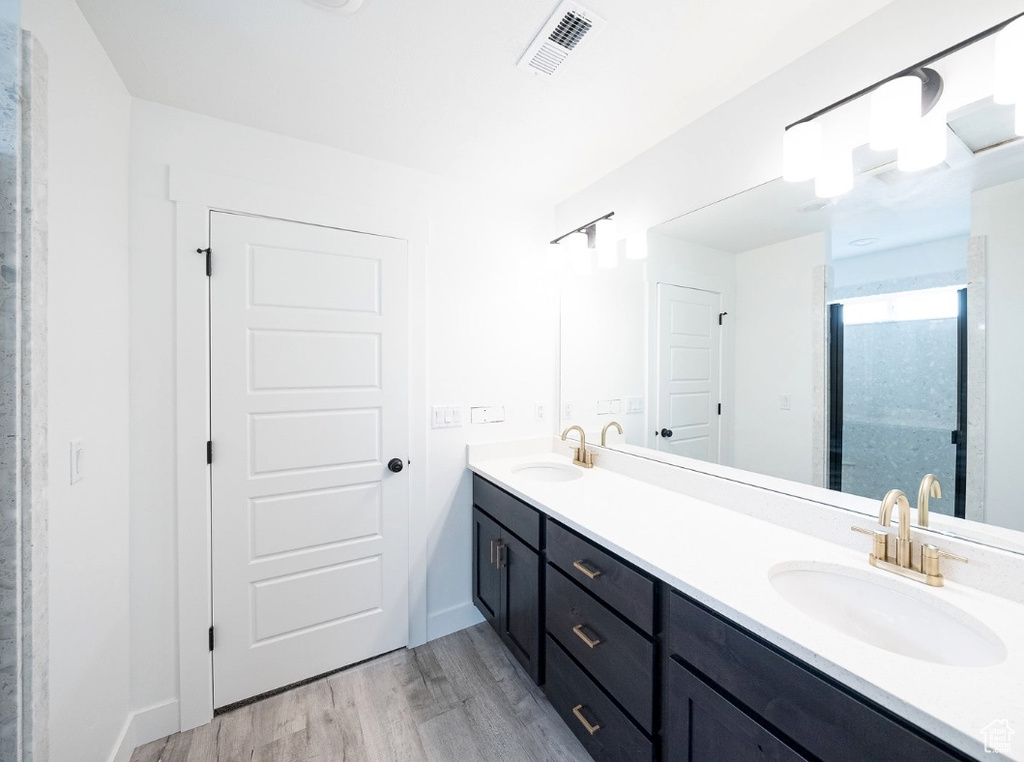 Full bath with double vanity, wood finished floors, and baseboards