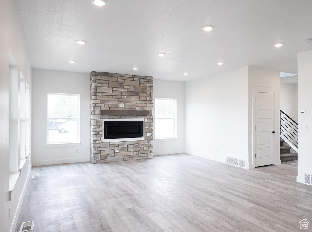 Unfurnished living room featuring stairway, healthy amount of natural light, wood finished floors, baseboards, and recessed lighting