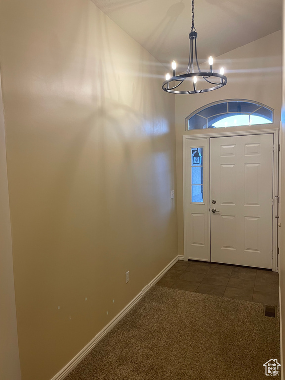 Foyer entrance with baseboards, dark carpet, a chandelier, and dark tile patterned flooring