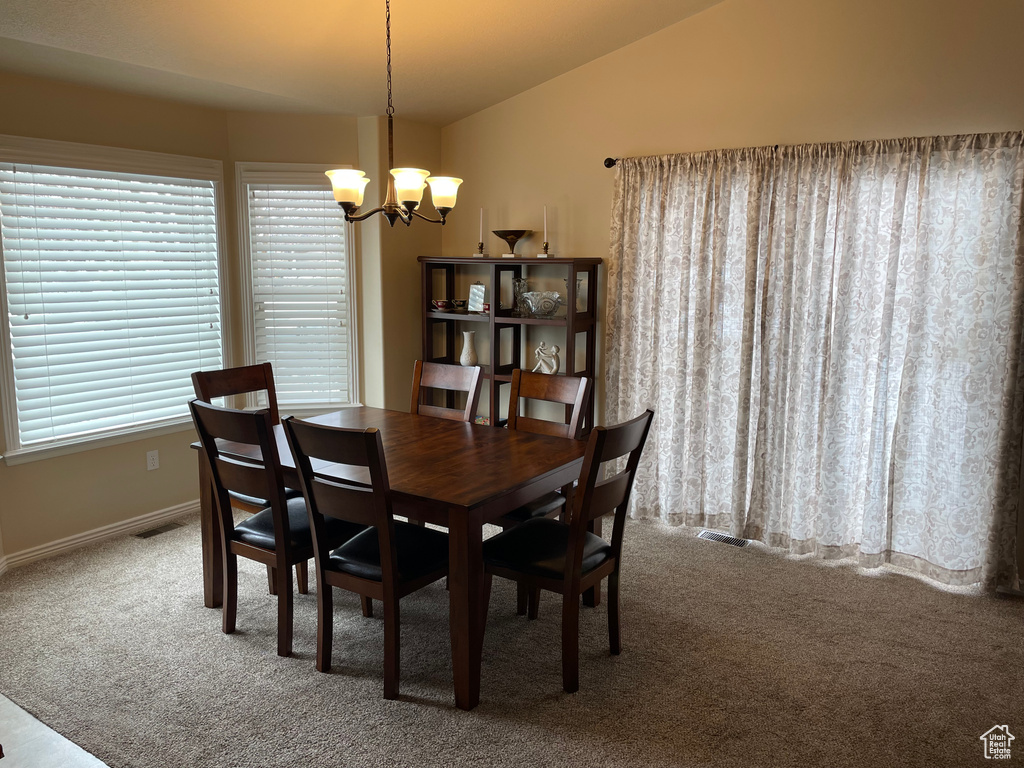 Dining room with carpet, baseboards, vaulted ceiling, and a notable chandelier