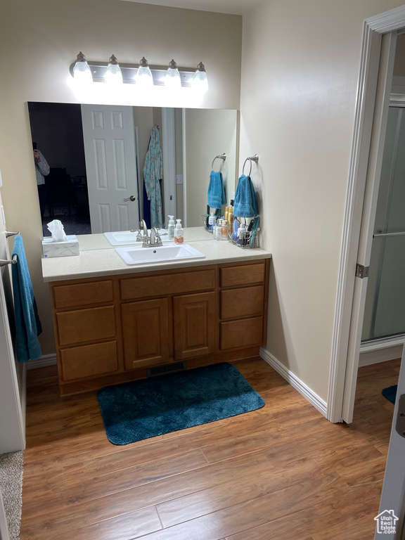 Bathroom with visible vents, vanity, a shower stall, wood finished floors, and baseboards