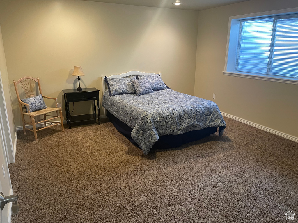 Bedroom featuring dark carpet and baseboards