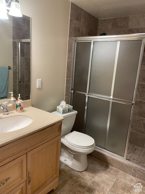Full bathroom featuring toilet, a stall shower, and vanity
