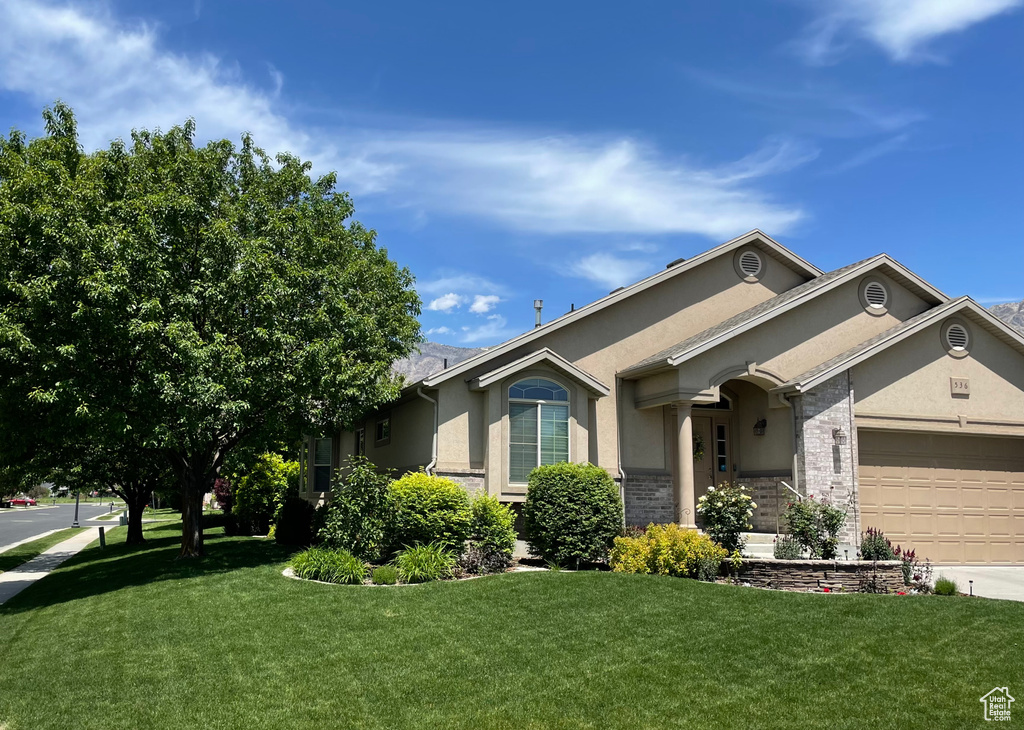 Ranch-style home with stucco siding, an attached garage, a front lawn, and concrete driveway