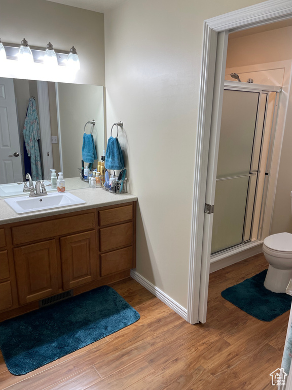Full bathroom featuring visible vents, toilet, vanity, a shower stall, and wood finished floors