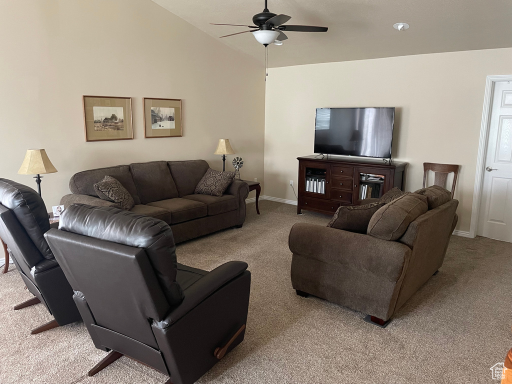 Living area featuring light carpet, vaulted ceiling, a ceiling fan, and baseboards