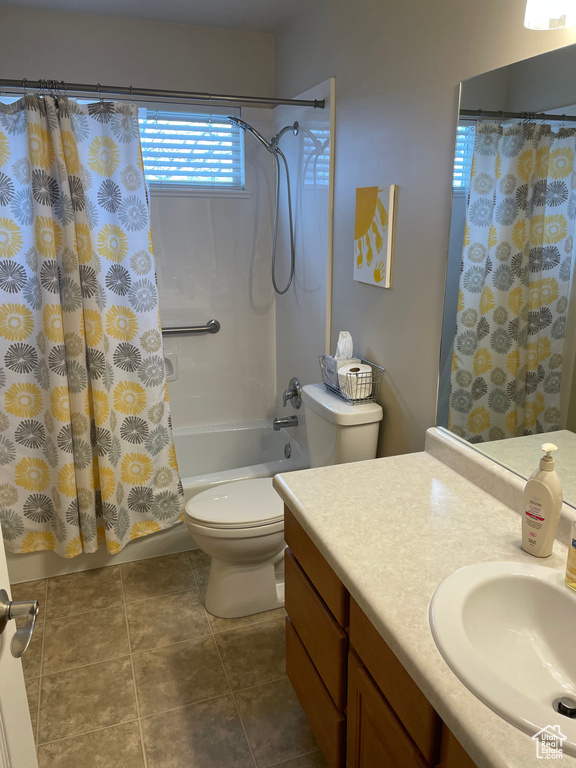 Bathroom with shower / bath combo with shower curtain, vanity, toilet, and tile patterned floors
