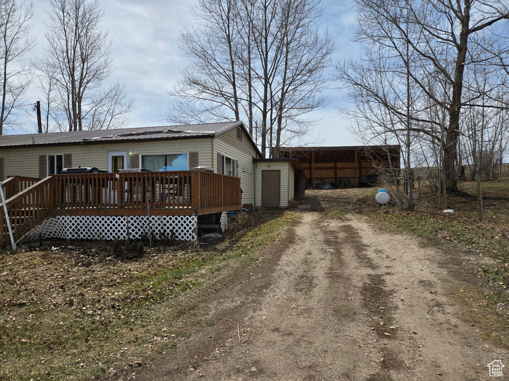 View of front of house featuring a deck, metal roof, and dirt driveway