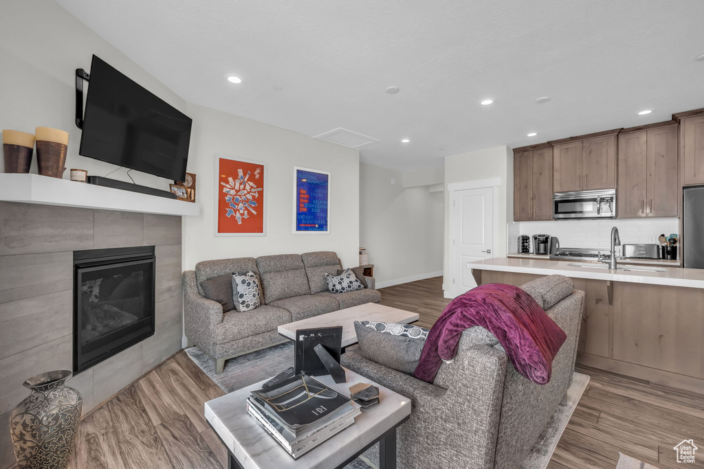 Living area featuring light wood-style flooring, recessed lighting, a tile fireplace, and baseboards