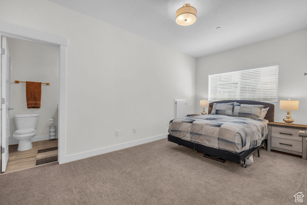 Bedroom featuring light colored carpet, baseboards, and connected bathroom