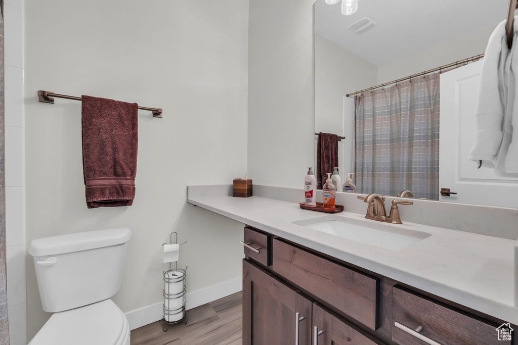 Full bath featuring vanity, toilet, wood finished floors, baseboards, and a shower with curtain