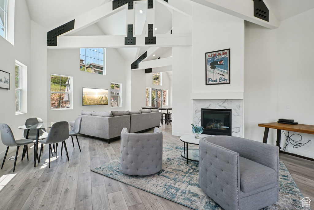 Living room with high vaulted ceiling, beamed ceiling, a premium fireplace, light wood-style flooring, and baseboards