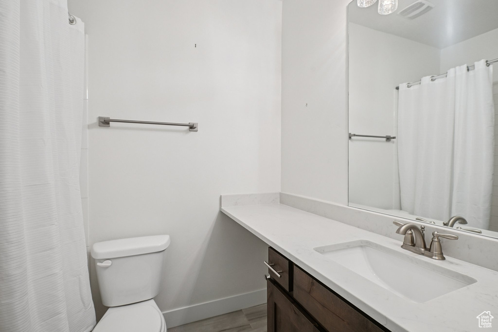 Full bath featuring toilet, vanity, baseboards, wood finished floors, and a shower with curtain