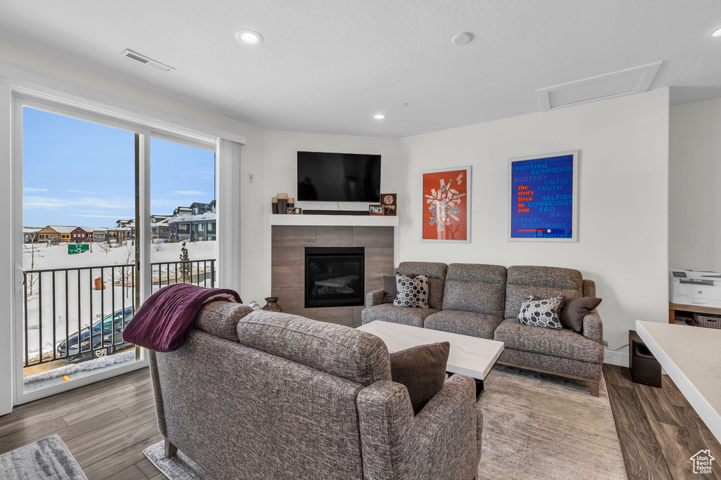 Living room with wood finished floors, a fireplace, and recessed lighting
