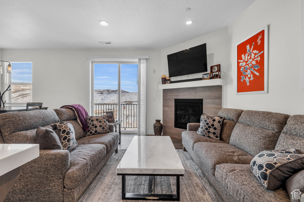 Living area with plenty of natural light, a tiled fireplace, and recessed lighting