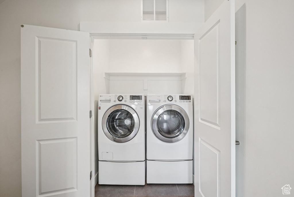 Laundry room featuring separate washer and dryer and dark tile patterned floors