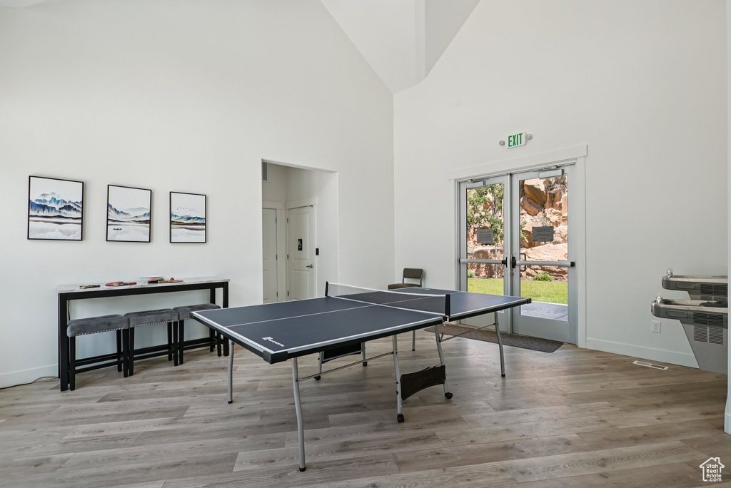 Recreation room with wood finished floors, baseboards, a high ceiling, and french doors