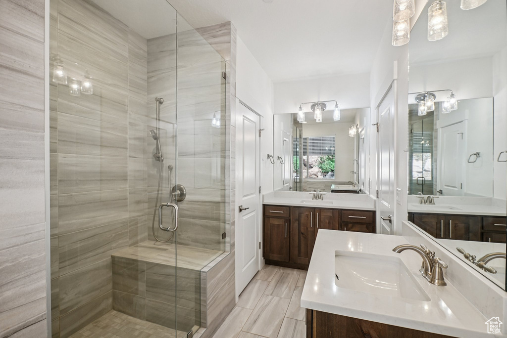 Bathroom featuring a shower stall and two vanities